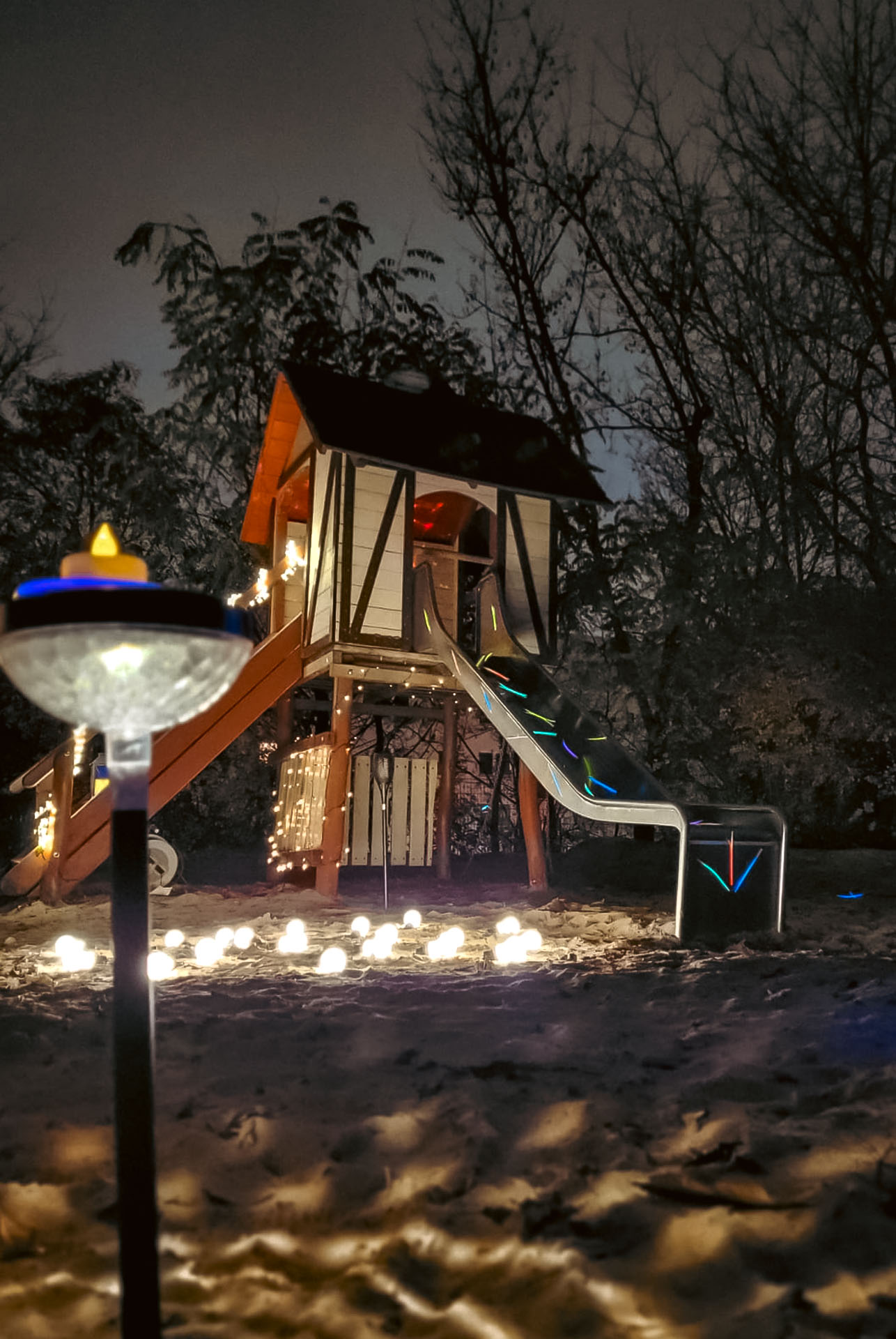 Eine Holzrutsche im Außenbereich der Kita Spatzenhaus Berlin, festlich dekoriert während des Lichterfests (© Lamine Schmidt).